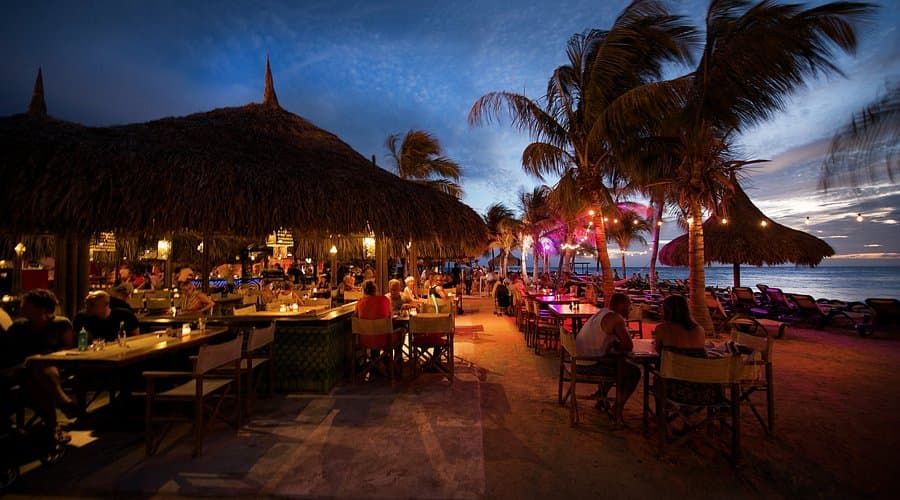 Beach club restaurant at night with palapa, string lights and ocean views on Curaçao